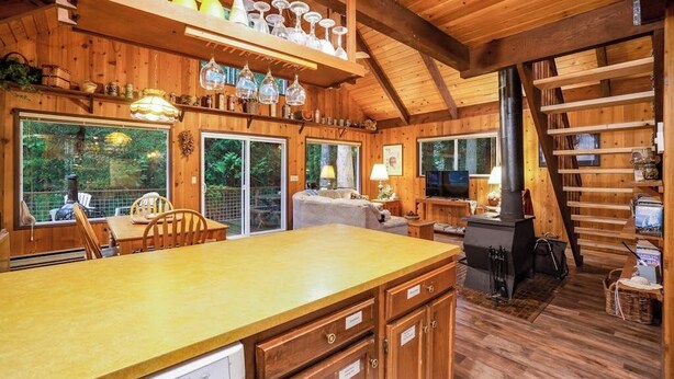 A wooden interior with a kitchen area, dining table, and a fireplace. - Quiet 2 BR Lopez Island Cabin Near Beach (Lopez Island)
