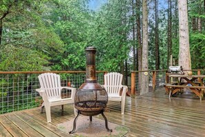Una terrazza con stufa a legna, due poltrone Adirondack bianche e un tavolo da picnic.
