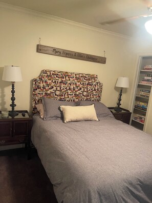 A bedroom with a patterned headboard, a grey bedspread, two bedside tables with lamps, a nightstand, and a wall-mounted sign. - Paradise in the woods 
Spacious 5-bedroom cabin in serene Oxford with AC (Oxford)