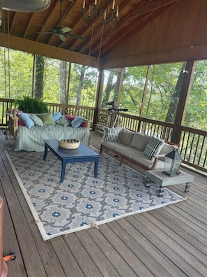 A covered porch with a wooden ceiling, a blue table, a sofa, and a patterned rug. - Paradise in the woods 
Spacious 5-bedroom cabin in serene Oxford with AC (Oxford)