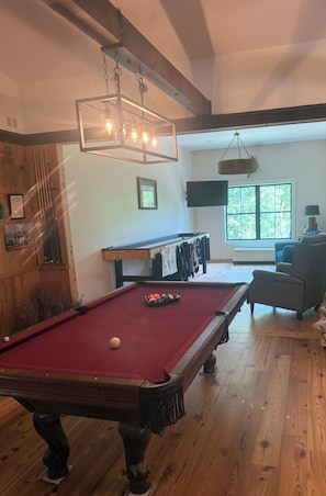 A pool table with balls, a television, and a window with a view of trees. - Paradise in the woods 
Spacious 5-bedroom cabin in serene Oxford with AC (Oxford)