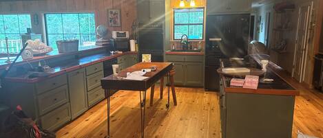 A kitchen with wooden cabinets, a central island, and a window overlooking greenery.