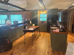 A kitchen with wooden cabinets, a central island, and a window overlooking greenery. - Paradise in the woods 
Spacious 5-bedroom cabin in serene Oxford with AC (Oxford)