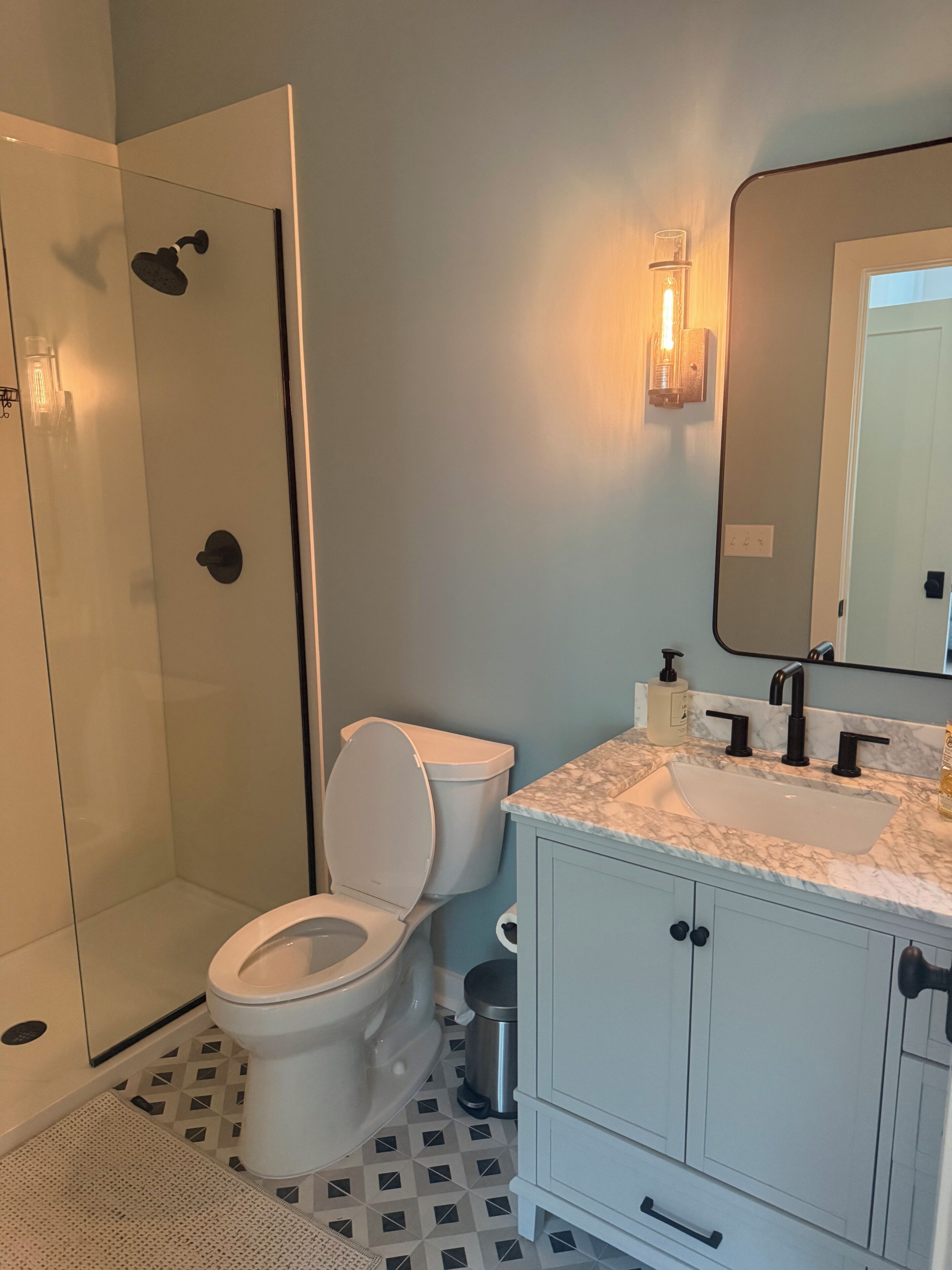 Een badkamer met toilet, wastafel, spiegel en douchecabine.