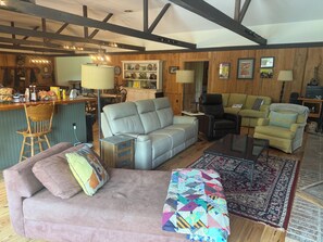 Un espacio habitable amplio con un sofá, sillones, una mesa de centro y una alfombra estampada.