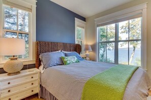 A bedroom with a bed, nightstands, and a view of the outdoors. - Stunning 4BR Waterfront Home in Eastsound with Private Sauna and Beach Access (Eastsound)