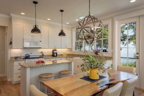 Una cocina moderna con armarios blancos, una isla central e iluminación colgante.