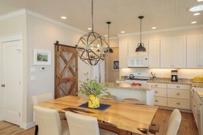 A dining area with a wooden table, chairs, and a hanging light fixture.