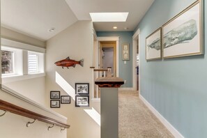 A hallway with a staircase, a fish sculpture, and framed pictures on the walls. - Stunning 4BR Waterfront Home in Eastsound with Private Sauna and Beach Access (Eastsound)