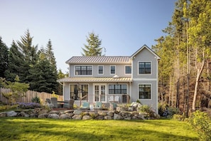 A two-story house with a covered porch, stone retaining wall, and a well-maintained garden.