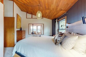 Une chambre avec un grand lit, un plafond en bois et une fenêtre donnant sur un beau paysage.