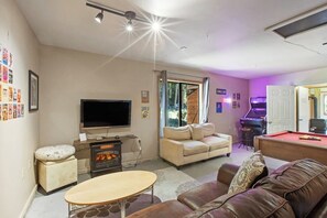 A living room with a flat-screen TV, a fireplace, a pool table, and a sofa. - Scenic Log Cabin with Hot Tub, Beach Access and Game Room (Freeland)