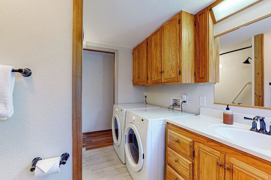 A compact bathroom with wooden cabinets, a white sink, and a washing machine.