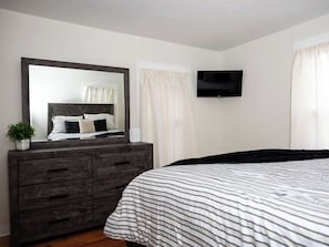 A bedroom with a bed, a dresser, a television, and a window with curtains. - Cozy 2-bedroom family friendly duplex in quaint East Hartford with office space (East Hartford)