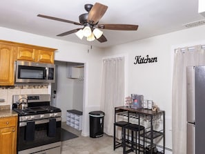 A compact kitchen with a stove, microwave, and a ceiling fan. - Cozy 2-bedroom family friendly duplex in quaint East Hartford with office space (East Hartford)