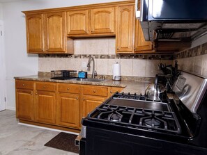 A kitchen with wooden cabinets, a gas stove, and a tiled backsplash. - Cozy 2-bedroom family friendly duplex in quaint East Hartford with office space (East Hartford)