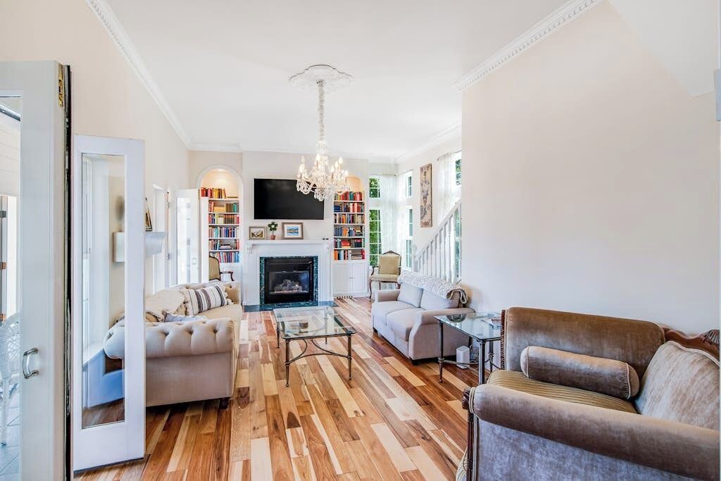 A spacious living room with a fireplace, a sofa set, a coffee table, and a bookshelf.