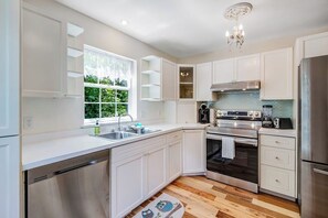 Een moderne keuken met witte kasten, een roestvrijstalen koelkast en een inbouwoven.