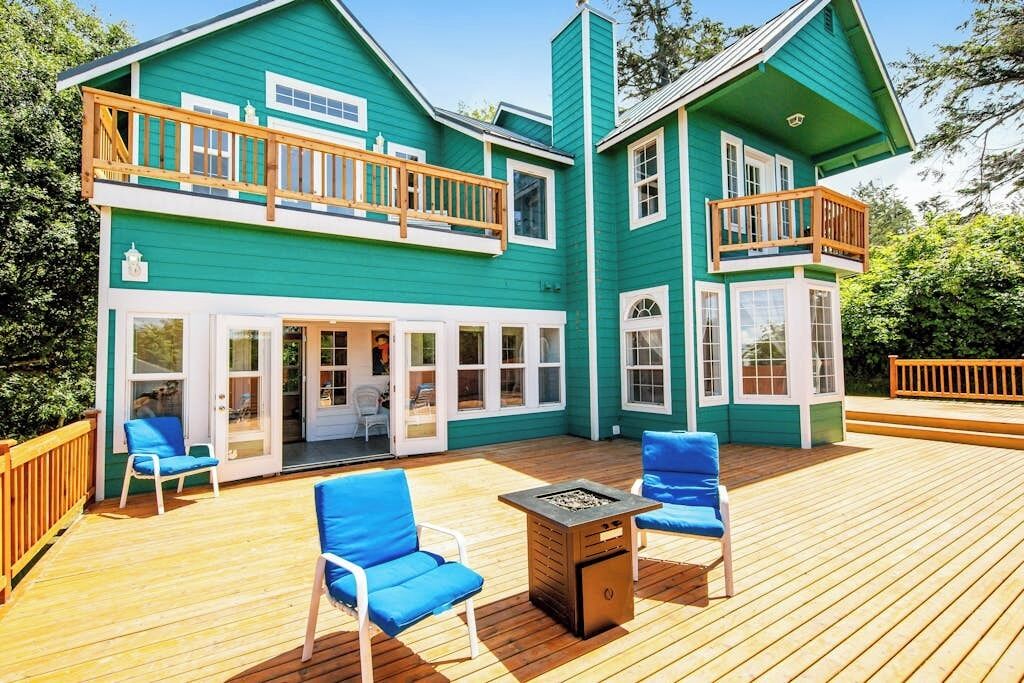 Une maison à deux étages dotée d’une terrasse, d’un espace salon extérieur et d’un foyer.
