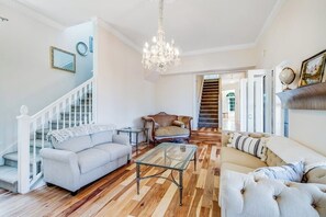 Ein großzügiger Wohnraum mit Treppe, einer Chandelieber und einem Sofa.