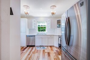 Una cucina moderna con mobili bianchi, elettrodomestici in acciaio inossidabile e pavimento in legno.