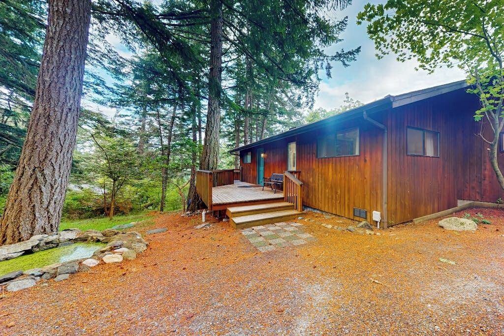 A cabin with a wooden exterior, a porch, and a stone pathway leading to the entrance.