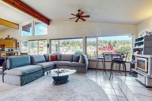 A spacious living room with a sectional sofa, a coffee table, and a dining area with bar stools. - Peaceful Island Retreat with Community Dock on Whidbey Island (Oak Harbor)