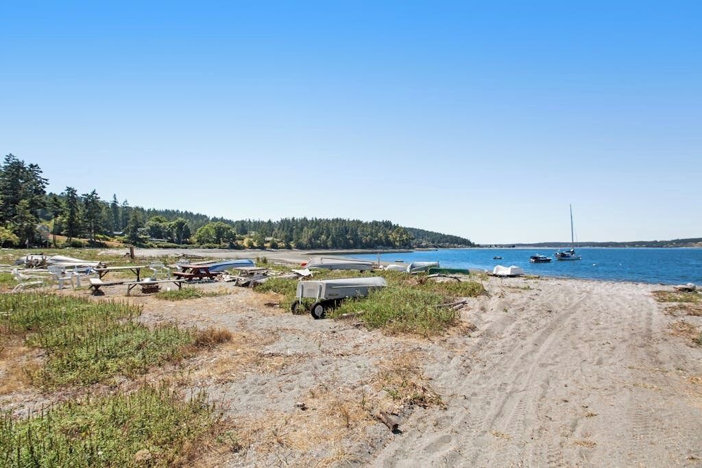 A beach with boats and a dirt path leading to the water.