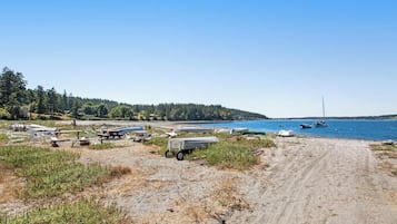 A beach with boats and a dirt path leading to the water.