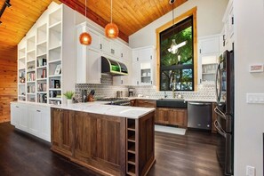 A modern kitchen with a central island, white cabinetry, and a large window.
