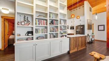 Une cuisine spacieuse avec des meubles blancs, un îlot central et un plafond en bois.