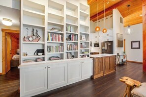 Una cocina amplia con armarios blancos, una isla central y techo de madera.