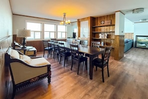 A dining area with a wooden table and chairs, a sofa, and a lamp.