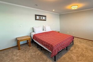A bedroom with a bed, a nightstand, a wall-mounted light fixture, and a framed picture.