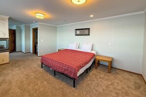 A bedroom with a bed, bedside tables, and a wall-mounted light fixture.