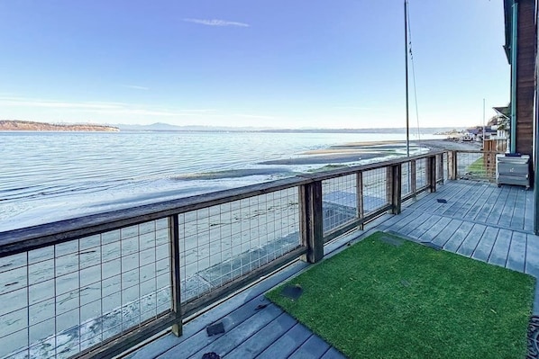 A wooden deck with a metal railing overlooking a body of water.