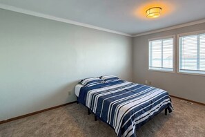 A bedroom with a bed, a window, and a ceiling light.