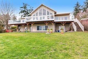 A two-story house with a covered porch and a staircase leading to the upper level. - Stunning 4 Bedroom Beachfront Home in Greenbank with Panoramic Water Views (Greenbank)