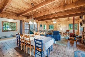 A wooden interior with a dining area, a sofa, and a fireplace. - Spectacular Waterfront Cabin in Eastsound with Private Deck and Mountain Views (Eastsound)