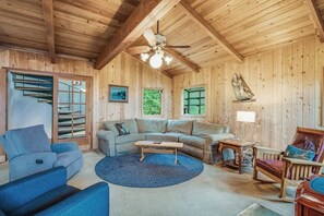 A wooden interior with a ceiling fan, a sectional sofa, a coffee table, and a rocking chair. - Spectacular Waterfront Cabin in Eastsound with Private Deck and Mountain Views (Eastsound)