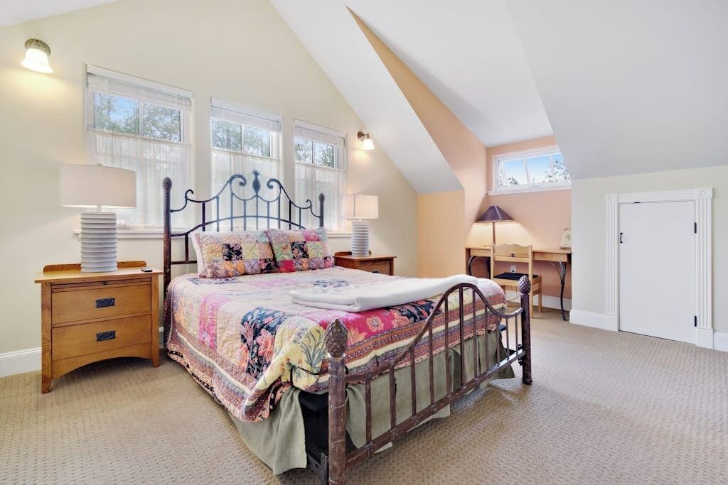 Une chambre à coucher avec un lit, des tables de chevet, un bureau et une fenêtre.