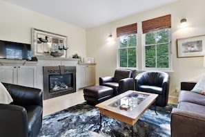 Ein Wohnzimmer mit Kamin, Ledersofas, einem Couchtisch und einem Fernseher.