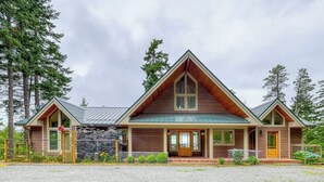A two-story log cabin with a prominent gable roof and a front porch. - Stunning Water View Retreat with Fireplace, Huge Deck, and Jetted Tub (Eastsound)