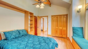 A bedroom with a bed, a ceiling fan, wooden wardrobes, and a bench. - Stunning Water View Retreat with Fireplace, Huge Deck, and Jetted Tub (Eastsound)