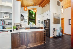 A modern kitchen with a large island, wooden cabinets, and pendant lighting. - Scenic Waterfront Home with Hot Tub and Three Unique Living Spaces (Coupeville)