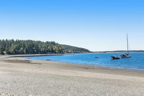 Ein Strand mit Booten, bewaldetem Gebiet und blauem Himmel.