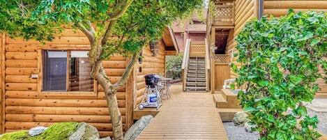 Uma cabana de madeira com deck de madeira que dá para uma porta, rodeada por árvores e vegetação.