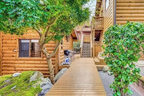 A wooden cabin with a wooden deck leading to a door, surrounded by trees and greenery. - Secluded Dog Friendly Studio with Hot Tub and Beach Access in Coupeville (Coupeville)