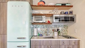 Una cocina compacta con un refrigerador blanco, un microondas y una tostadora.