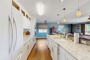 A modern kitchen with white cabinetry, a wooden floor, and pendant lighting. - Stunning Waterfront Home with Private Dock and Sauna in Oak Harbor (Oak Harbor)